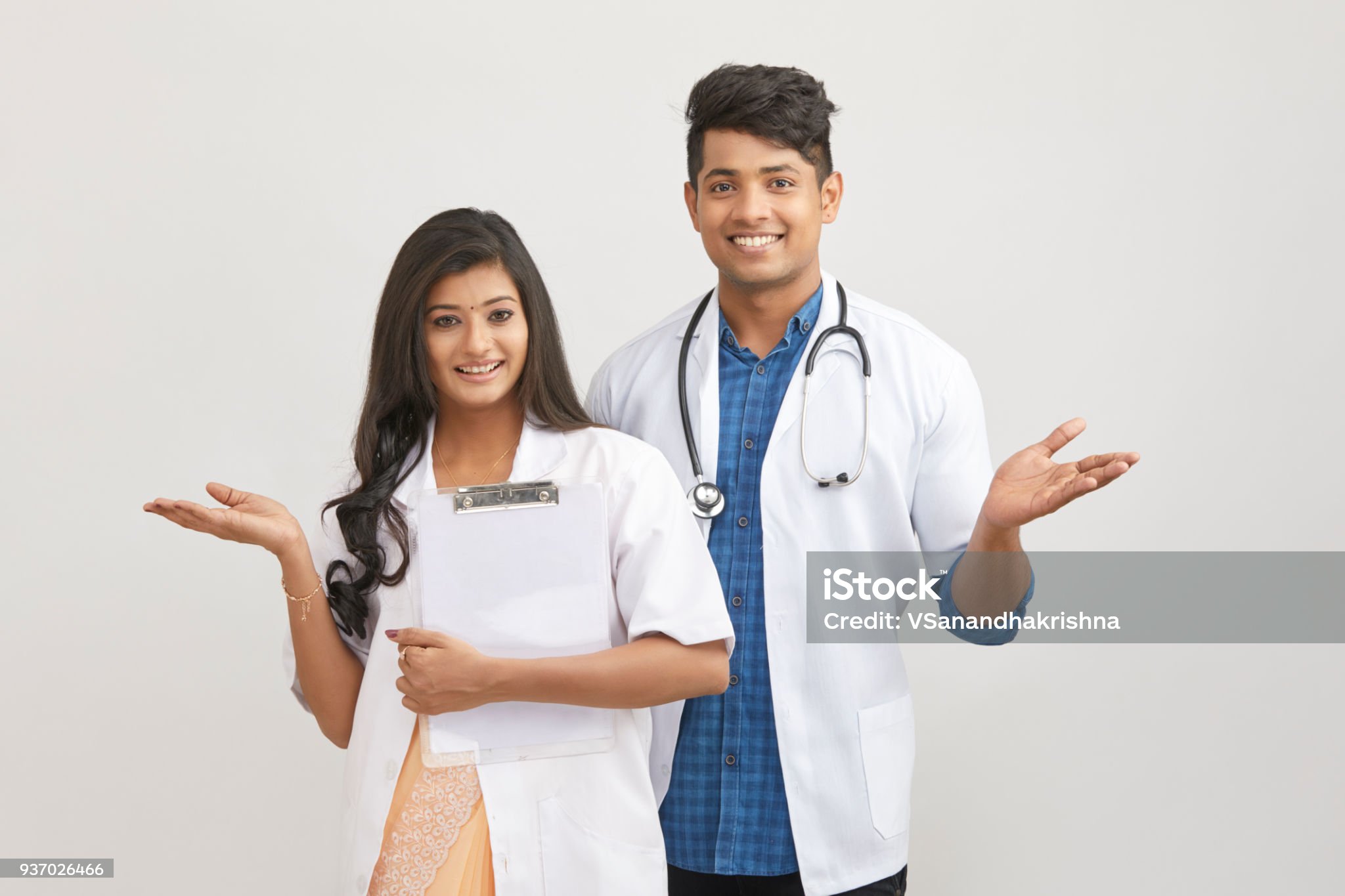 Indian young male and female doctor greeting against white.